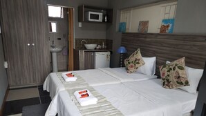 A hotel room with a double bed, a small kitchenette, a sink, and a microwave. - Room-home of Peace and Tranquility (Pretoria)