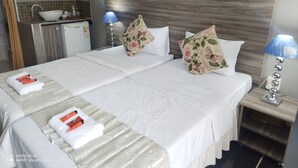 A hotel room with a double bed, two pillows, a bedside table with a lamp, a microwave, and a small kitchenette. - Room-home of Peace and Tranquility (Pretoria)