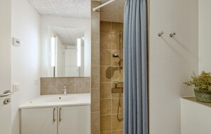 A modern bathroom with a shower, a sink, and a mirror.