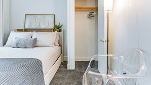 Egy hálószoba, amelyben található egy ágy, egy éjjeliszemélyzet, egy átlátszó szék és egy ajtó, amely a fürdőszobába vezet.