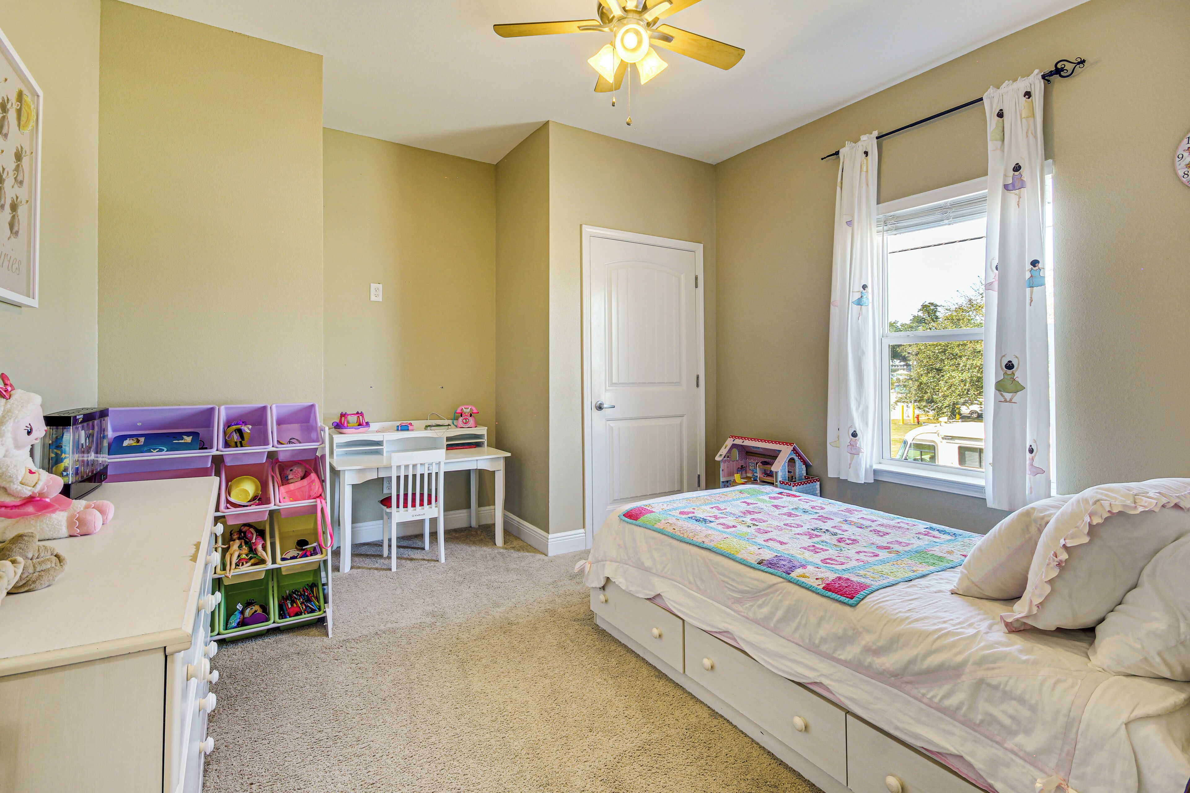A bedroom with a bed, a desk, and a window.
