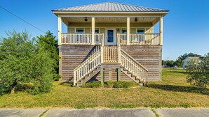 A two-story wooden building with a balcony, a front staircase, and a metal roof.