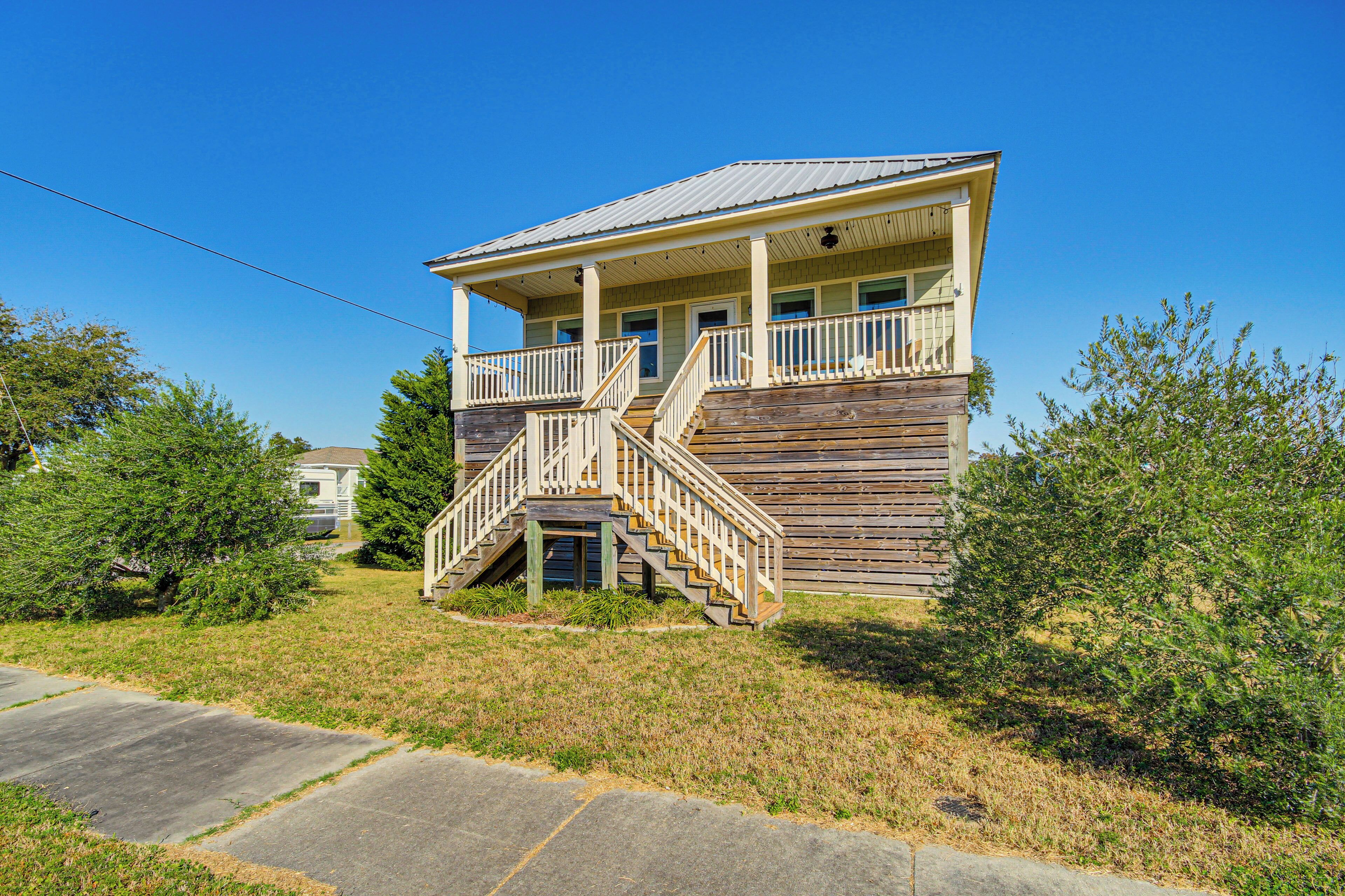 A two-story wooden house with a porch and a staircase leading to the second floor.