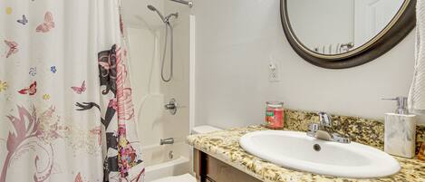 A bathroom with a shower, toilet, sink, and a mirror.
