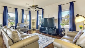 A living room with leather sofas, a flat-screen TV, and a ceiling fan.