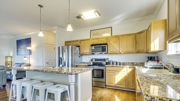 A modern kitchen with wooden cabinets, stainless steel appliances, and a granite countertop.