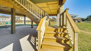 A wooden staircase leading to a covered area with a view of houses in the background.
