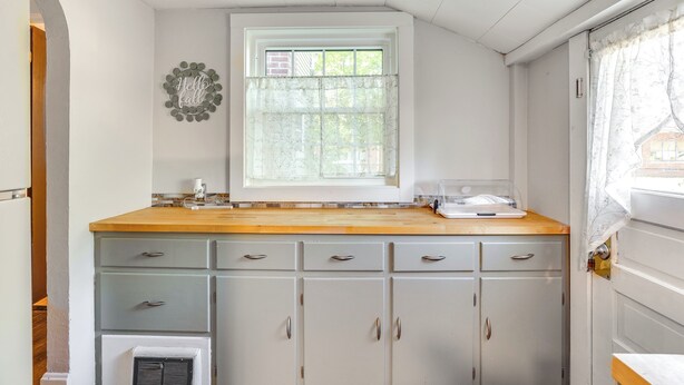 A kitchen with a window, a wooden countertop, and light gray cabinets. - Large Yard & Fire Pit: Pet-friendly Ravenna Home! (Ravenna)