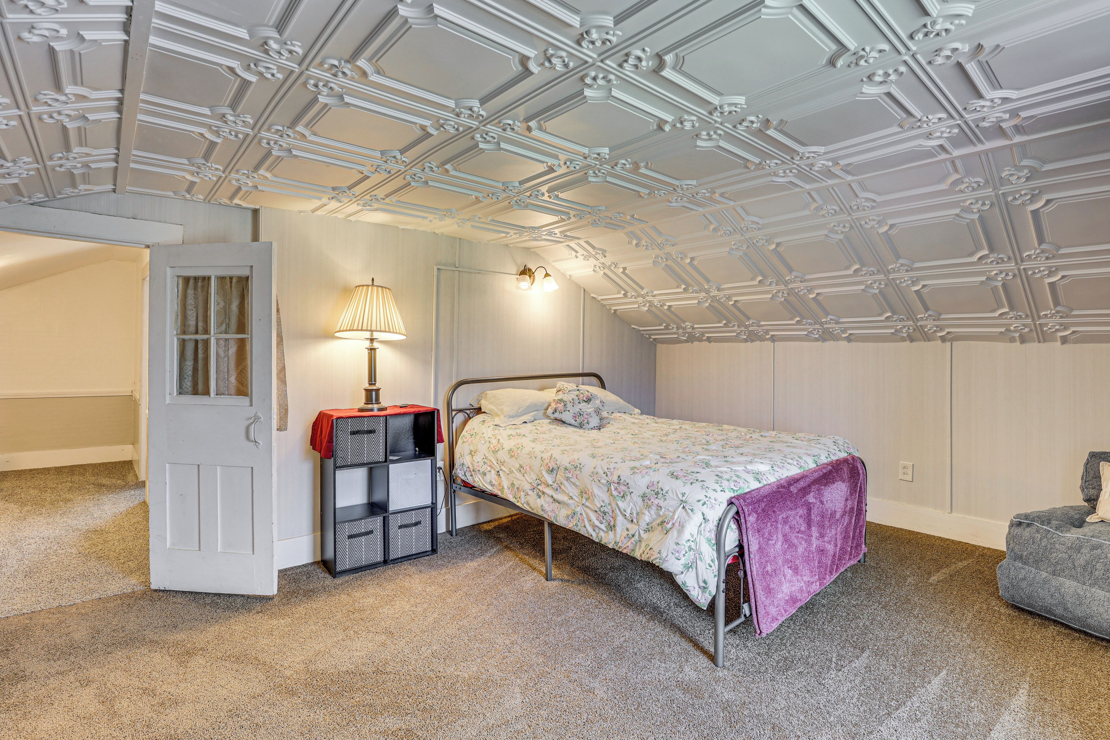 A bedroom with a bed, a nightstand, a lamp, and a wardrobe.