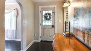 A hallway with a wooden bench, a door with a window, and a wall-mounted light fixture. - Large Yard & Fire Pit: Pet-friendly Ravenna Home! (Ravenna)