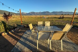 Mesa y sillas dispuestas al aire libre con vista a la montaña.