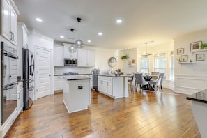 A spacious kitchen with white cabinetry, a central island, and a dining area with a table and chairs.
