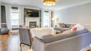 Een moderne woonkamer met een grijze bank, een zachte witte plaid en een open haard.