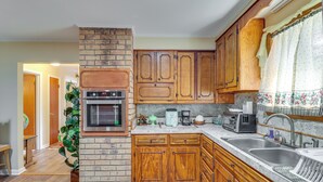 A kitchen with wooden cabinets, a brick oven, a sink, and a countertop with various appliances. - 2 Mi to Dtwn Natchez: Cozy Home w/ Yard & Patio! (Natchez)