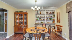 A dining area with a round wooden table, four chairs, a chandelier, and a cabinet with glass doors. - 2 Mi to Dtwn Natchez: Cozy Home w/ Yard & Patio! (Natchez)