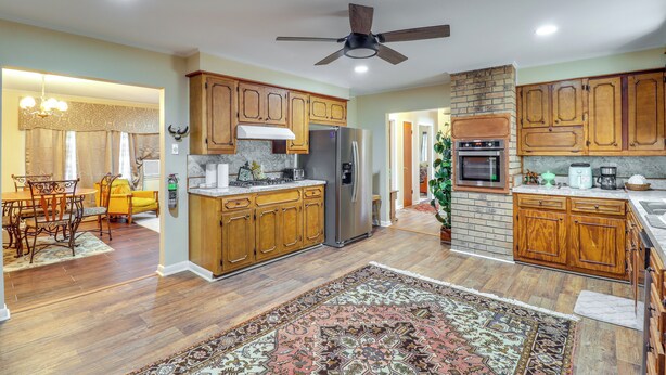 A spacious kitchen with wooden cabinets, a central island, and a ceiling fan. - 2 Mi to Dtwn Natchez: Cozy Home w/ Yard & Patio! (Natchez)