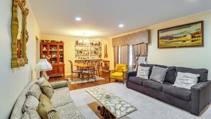 A living room with a sofa, a coffee table, a dining table with chairs, and a bookshelf. - 2 Mi to Dtwn Natchez: Cozy Home w/ Yard & Patio! (Natchez)