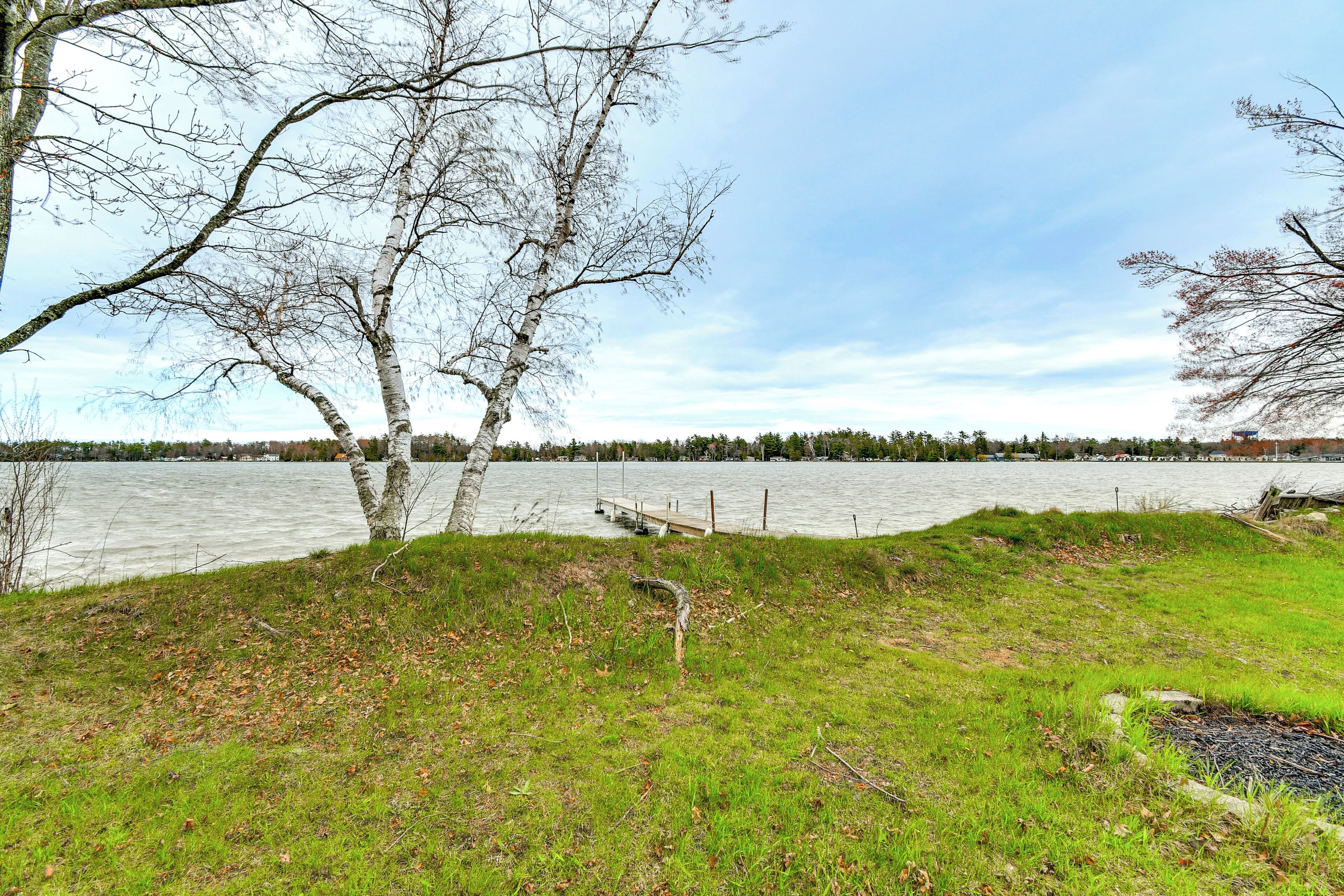 Een gazon met bomen en een steiger die in het water reikt.