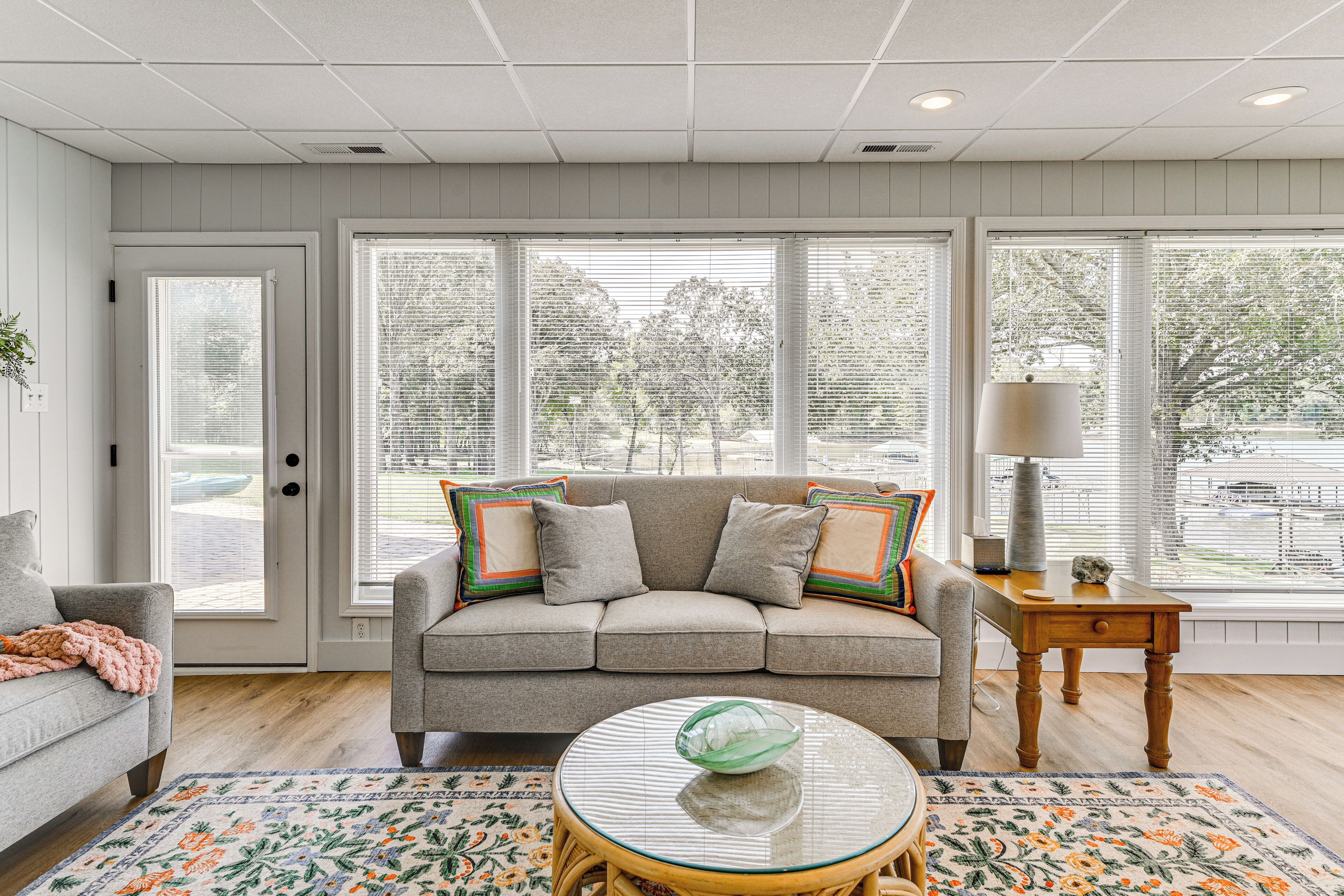 A living room with a sofa, a round coffee table, and a window with blinds.