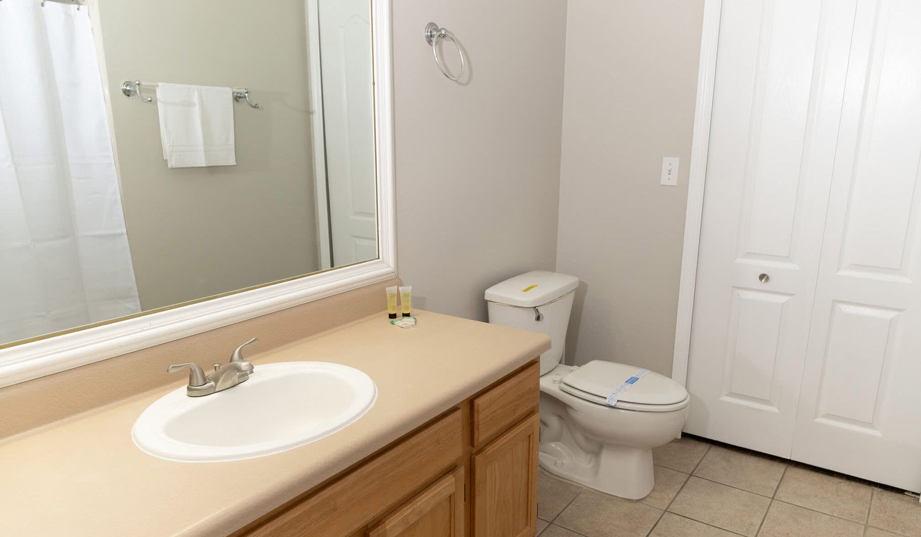 A bathroom with a sink, mirror, toilet, and a door.