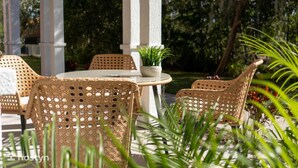 A patio area with wicker furniture, a round table, and a potted plant. - Magical Themed 3BR Townhouse Near the Parks (Kissimmee)