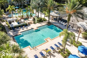 A resort pool area with multiple lounge chairs, palm trees, and a clear blue pool.