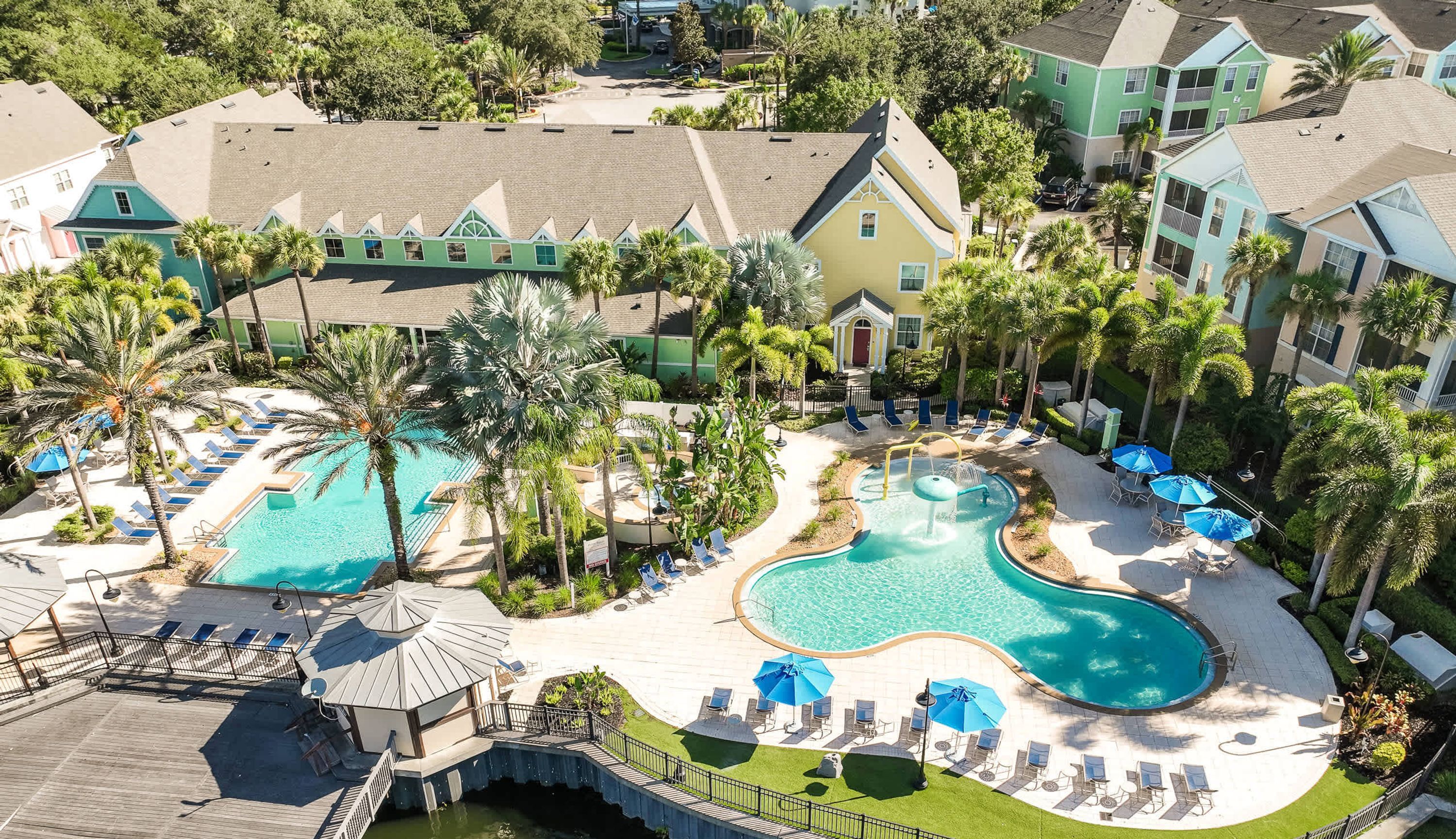 A resort with two swimming pools, palm trees, and lounge chairs.