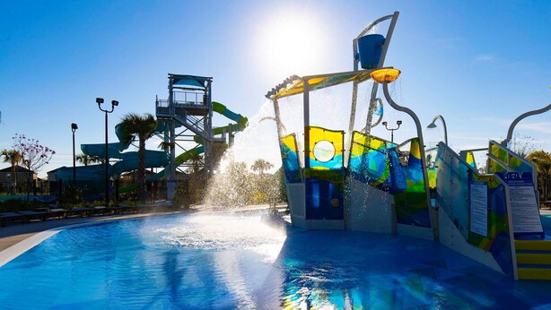 A water park with a pool, slides, and a water fountain. - Luxury 6BR Villa w Pool Jacuzzi Fun in Orlando (Kissimmee)