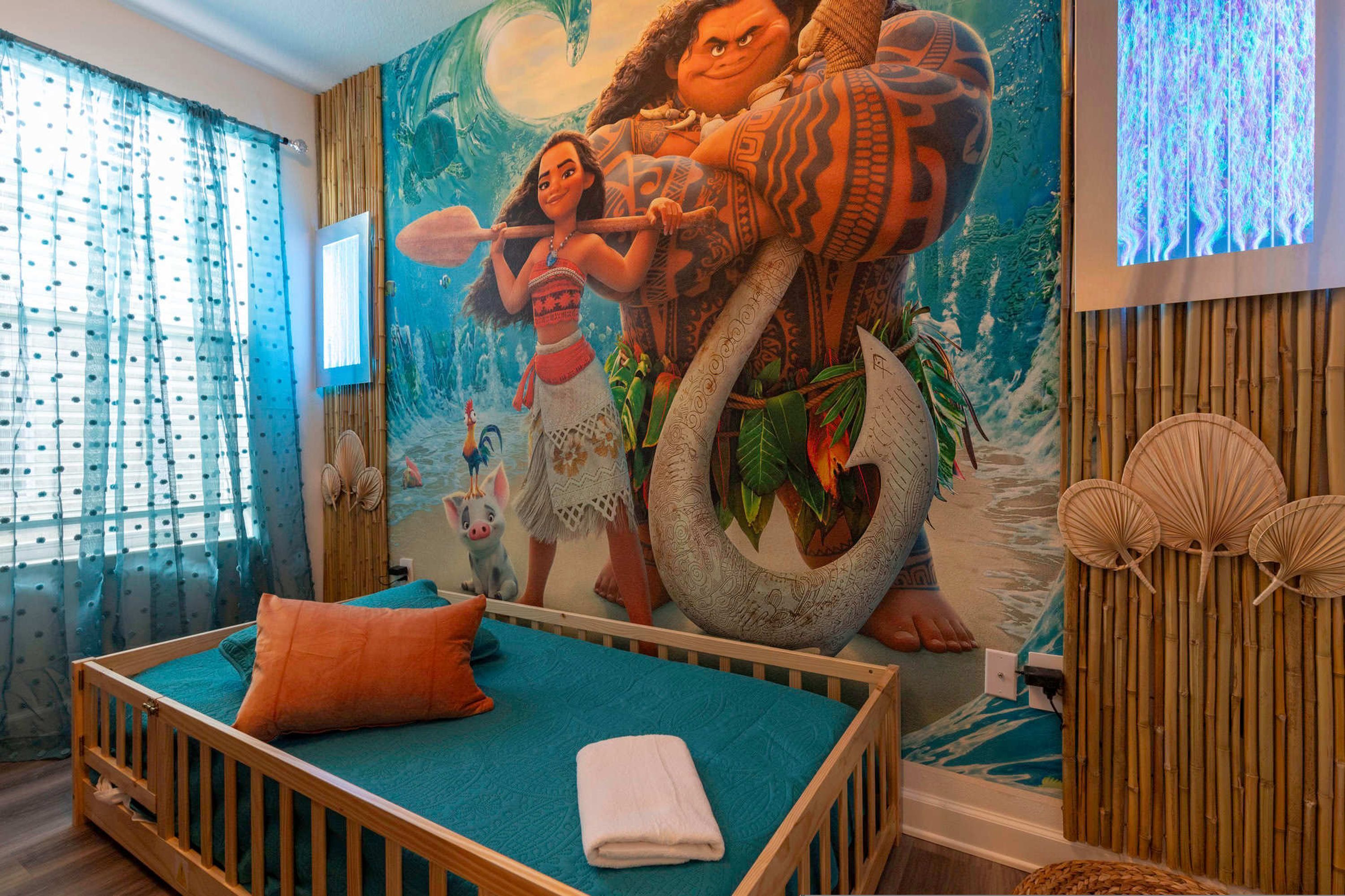 A room with a bed, a mural, and a television.
