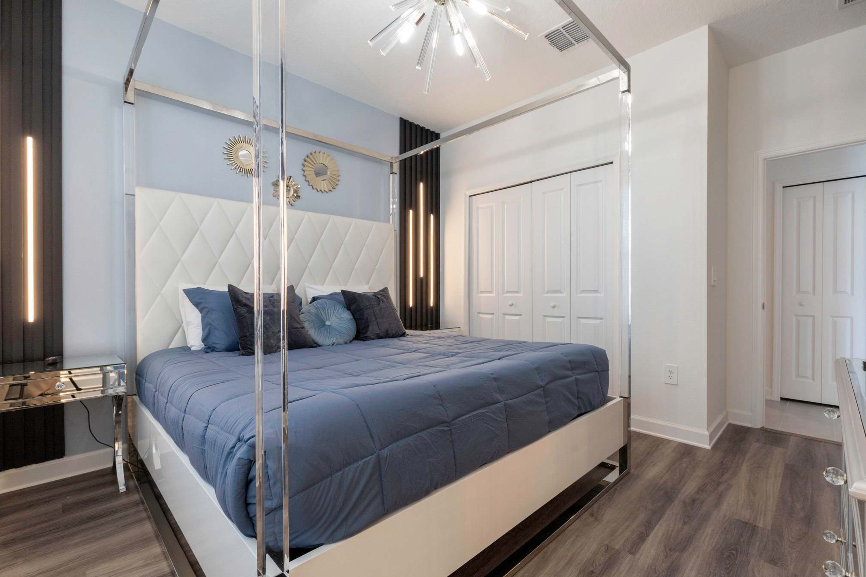 A modern bedroom with a large bed, a glass canopy, and a white wardrobe.