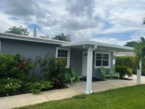 A house with a porch, green chairs, and a number '1618' on the wall.