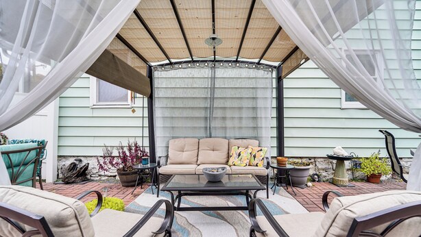 An outdoor patio with a cushioned seating area, a glass-top coffee table, and a pergola with a mesh canopy. - Grill, Dine & Relax Outside: Home in Tyrone! (Tyrone)
