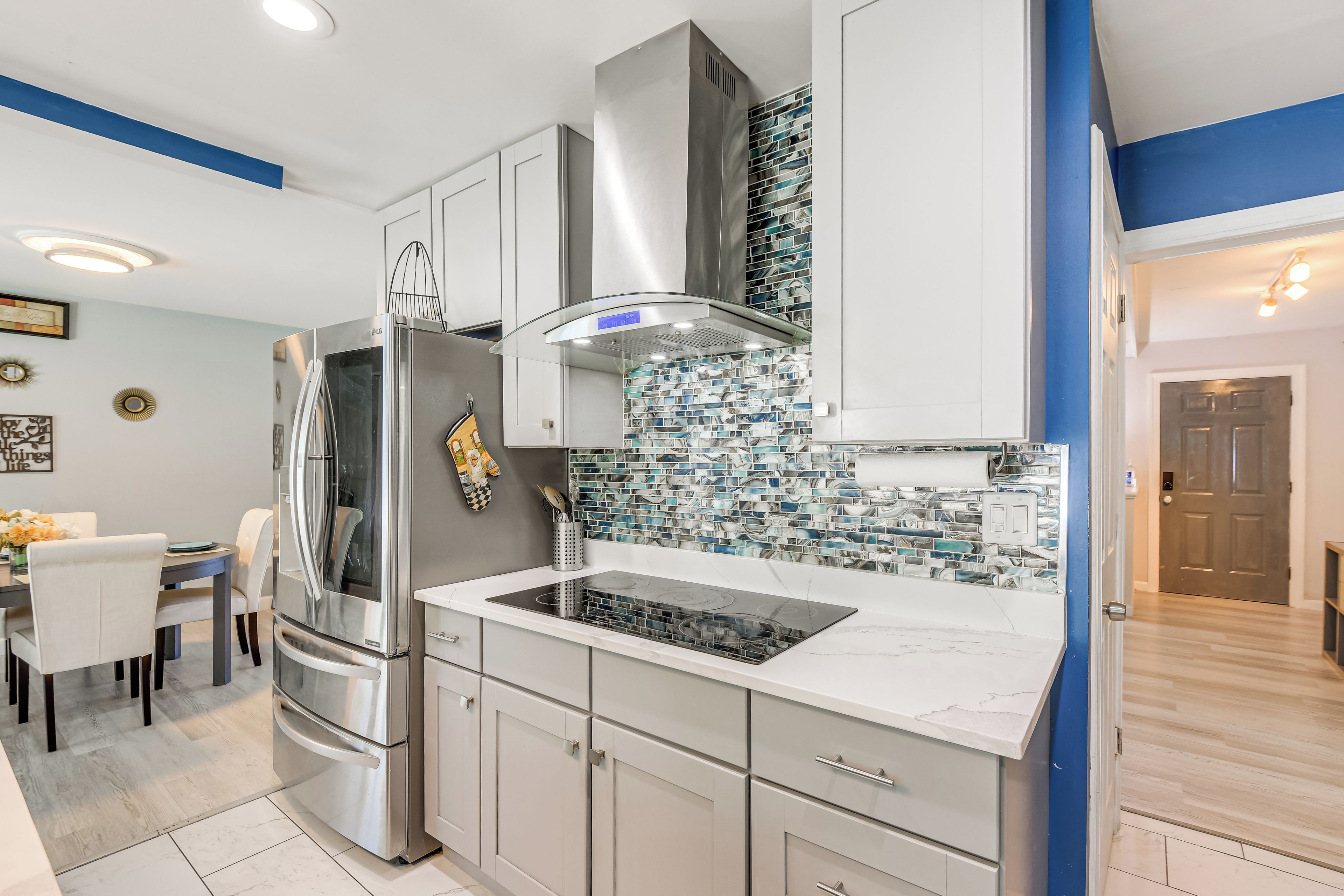 Una cocina moderna con electrodomésticos de acero inoxidable, armarios blancos y una pared de acento azul.
