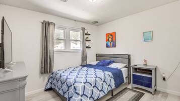 A bedroom with a bed, a nightstand, a dresser, a window with curtains, a painting on the wall, and a rug on the floor.