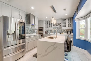 Una cocina moderna con electrodomésticos de acero inoxidable, armarios blancos y una pared de acento azul.