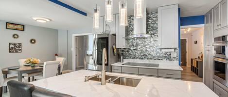 A modern kitchen with a central island, stainless steel appliances, and pendant lighting.