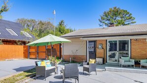A patio area with outdoor furniture, a green umbrella, and a brick building with a sliding glass door. - Pets Welcome: Quiet Silver Spring Retreat! (Silver Spring)