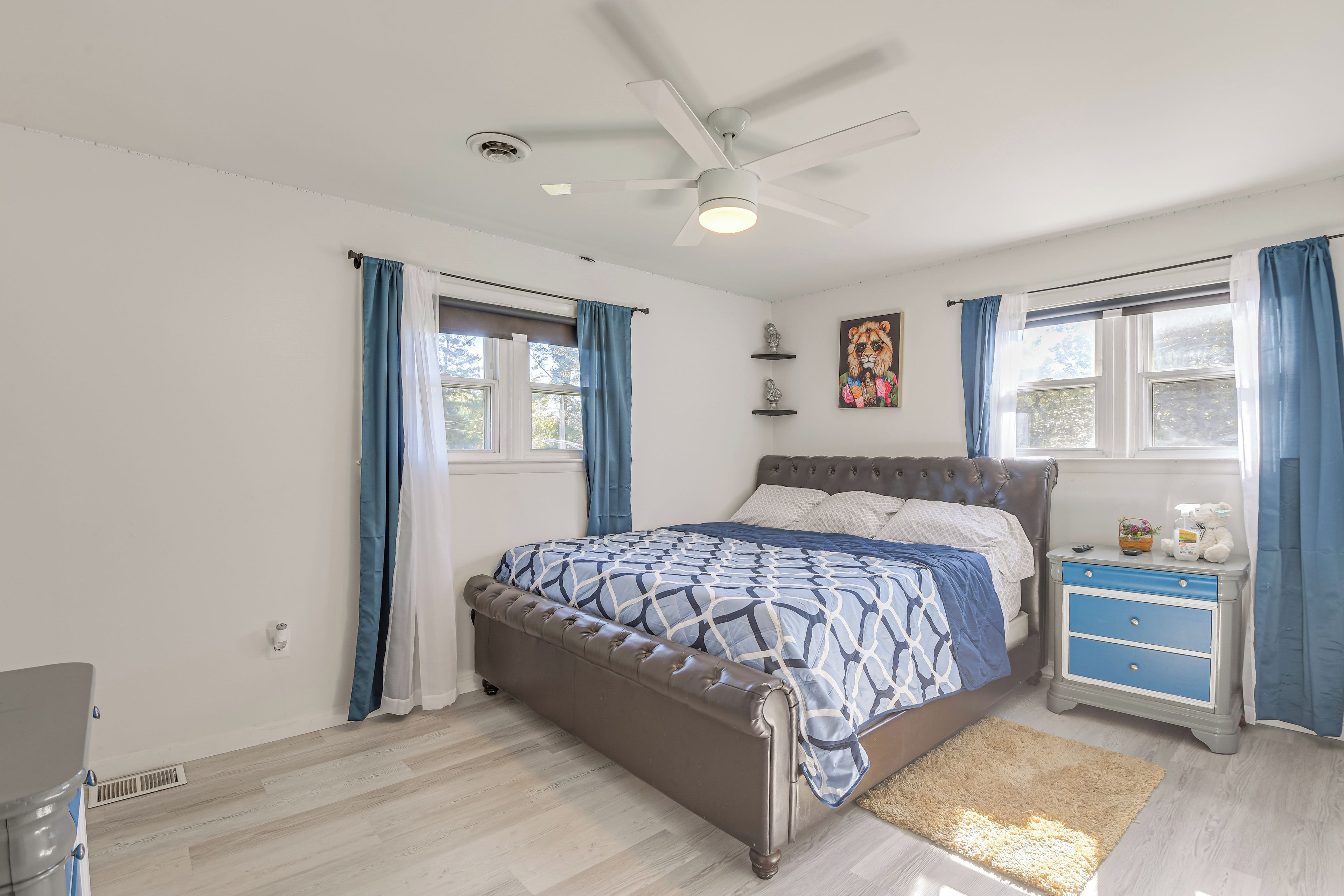A bedroom with a bed, nightstand, and ceiling fan.