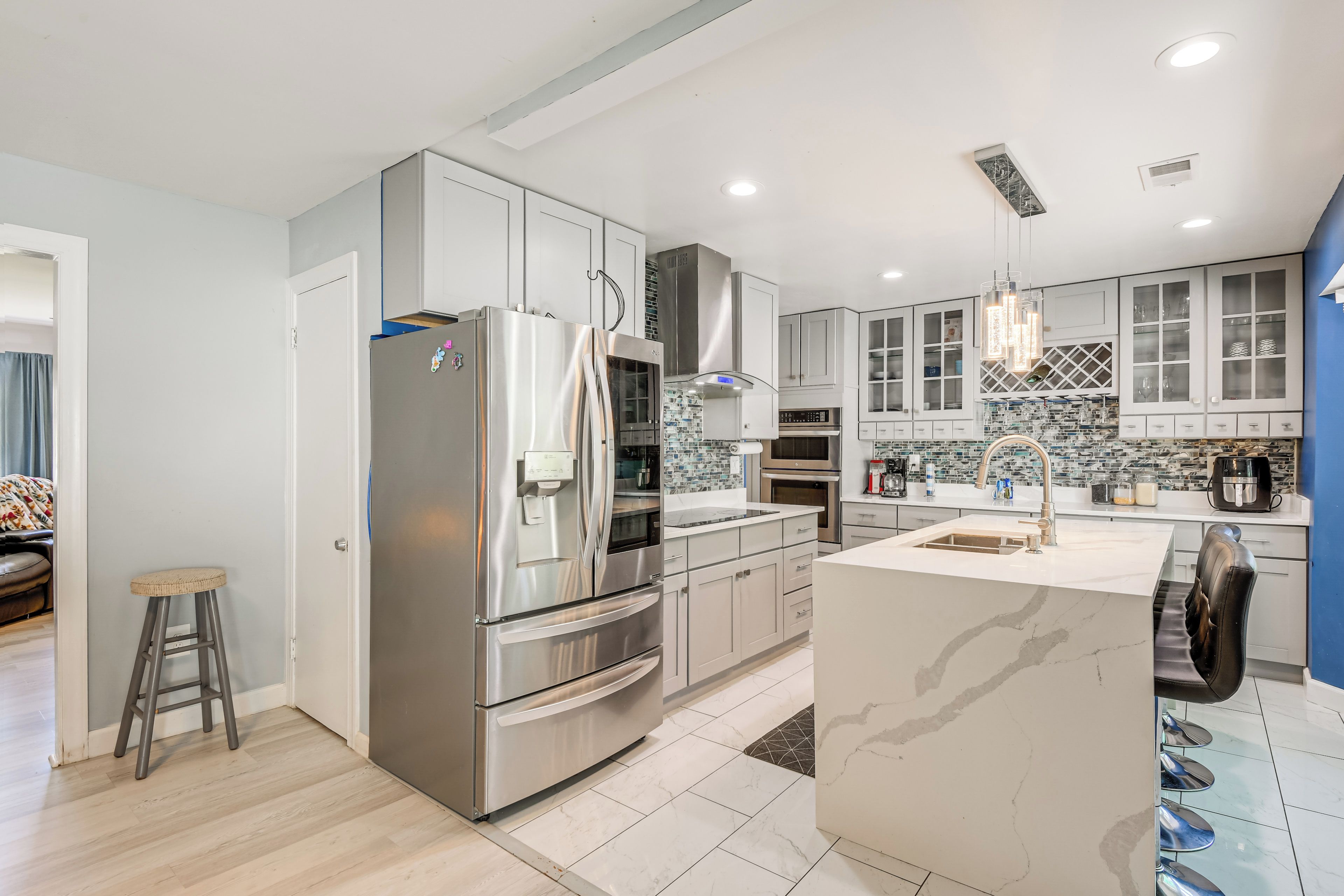 A modern kitchen with stainless steel appliances, a marble island, and a bar area.