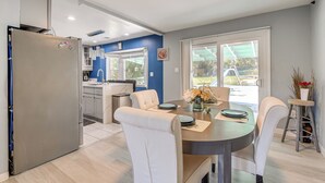 A modern kitchen with a built-in refrigerator, a dining area with a round table and white chairs, and a view of the outdoors through large windows. - Pets Welcome: Quiet Silver Spring Retreat! (Silver Spring)