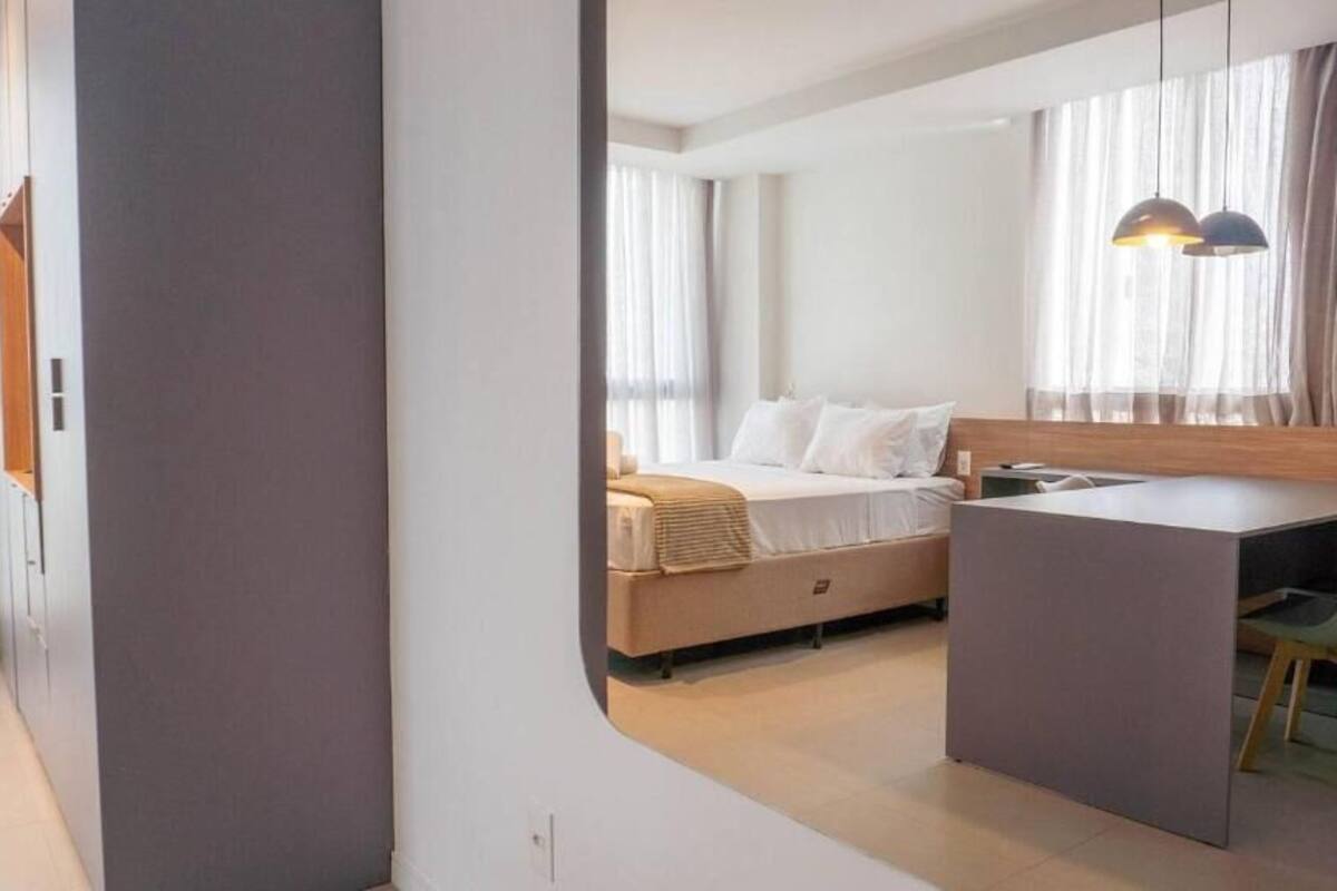 A modern bedroom with a bed, bedside table, and a desk area.