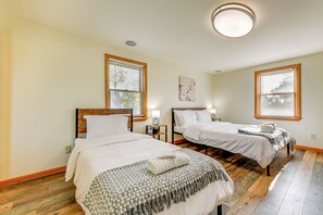 Ett hotellrum med två sängar, trägolv och en taklampa.