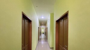 Un long couloir étroit, avec des portes de part et d’autre, qui mène à une pièce lumineuse au bout.