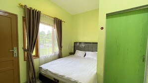 Une chambre à coucher avec un lit, des rideaux, une porte verte et une fenêtre donnant sur un paysage agréable.