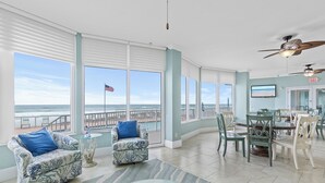 Una habitación amplia con ventanas grandes, una zona de comedor y un ventilador de techo.