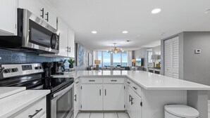 Una cocina moderna con armarios blancos, una estufa de acero inoxidable y una isla grande.