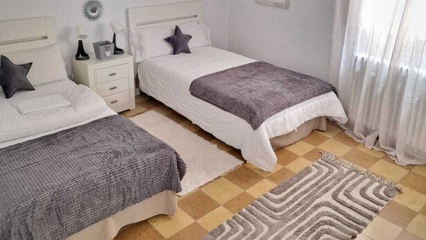 A bedroom with two beds, a nightstand, a lamp, and a ceiling light. - THE OLD WINE STATION APARTAMENTS in the very center of the city. (Haro)