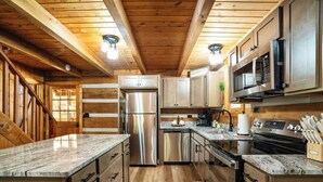 Une cuisine moderne avec des poutres en bois, des appareils en acier inoxydable et des plans de travail en marbre.