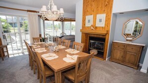 A dining room with a wooden table set for six, a fireplace, and a view of the outdoors. - Earnest, Ships Watch Community in Duck, NC (Duck)