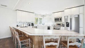 A modern kitchen with white cabinets, stainless steel appliances, and a large island with bar stools.